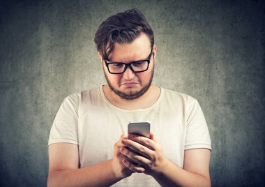 Öylesine üzgün genç adam üzgün ve kasvetli Smartphone cep telefonu ile saldırgan ileti aldı