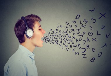 Kulaklık müzik dinleme ve gri üzerine ağzından çıkan harfleri ile şarkı adam yan görünüm