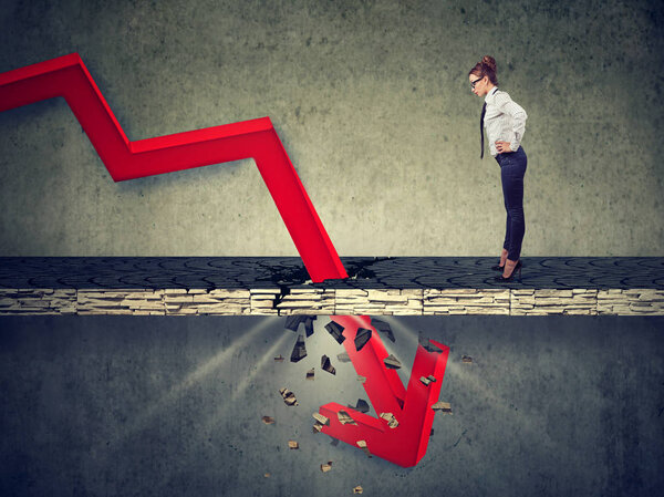 Любопытная обеспокоенная деловая женщина смотрит вниз на падающую красную стрелу, проходящую через бетонный пол
.