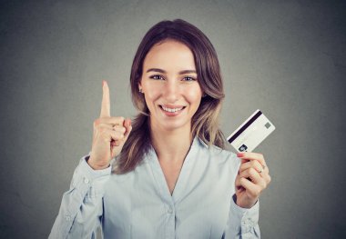 Parmak ve gösteren yeni kredi kartı kameraya gülümseyen tutarak en iyi bankacılık teklif olan genç kadın resmi