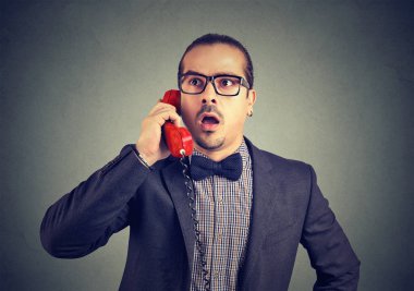 Zarif hayran adam uzakta gri arka plan üzerinde seyir telefon görüşmesi yaparken hayrete seyir gözlük