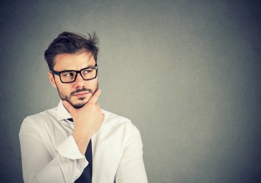 Genç adam ararken ve yeni iş stratejisi planlama ve gri arka plan üzerinde fikir oluşturma tefekkür sakallı