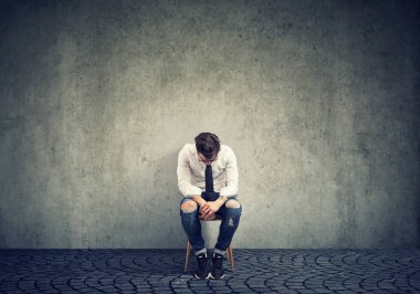 Kötü şans sandalye gri arka plan üzerinde tek başına oturan ile depresif adam üzgün 