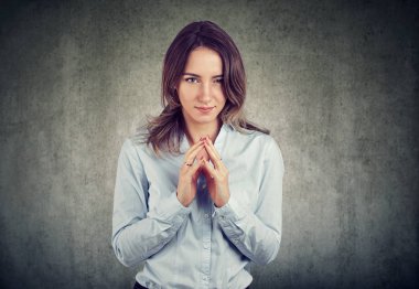 Gri arka plan üzerinde izole bir şey komplo kurnaz, entrikacı bir kadın portresi. Negatif insan duyguları, yüz ifadesi, duygu, tutum