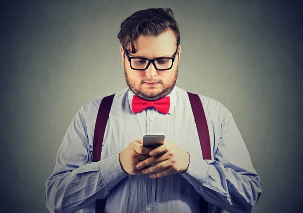 偏心胡子商业男子与红色弓领带在眼镜使用智能手机 — 图库照片