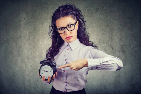 Mujer Negocios Gafas Mirando Seriamente Cámara Apuntando Reloj Despertador Mostrando —  Fotos de Stock