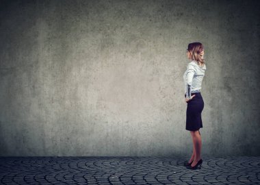 Gri duvarın önünde duran ve sorunu çözmek için çaba düşündüğünü işkadını yan görünüm