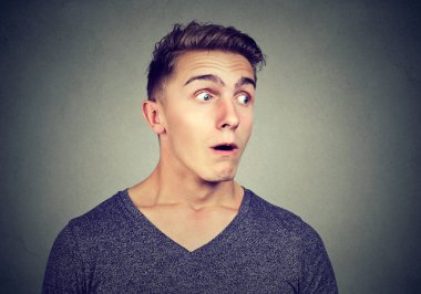 Süre gizli dinleme ve uzak gri arka plan üzerinde seyir süper hayran görünen genç casual adam 