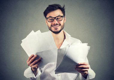 Kağıt belgeleri ile iyi sonuçlar üzerinden seyir ve gri arka plan üzerinde gülümseyen bardakları mutlu genç adam
