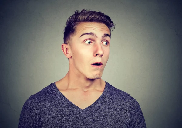 Süre gizli dinleme ve uzak gri arka plan üzerinde seyir süper hayran görünen genç casual adam 