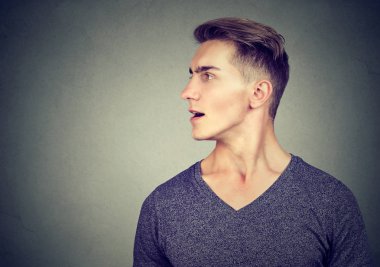 Yakışıklı delikanlı ağız ile konuşurken rahat kıyafet profil uzak gri arka plan üzerinde seyir açıldı