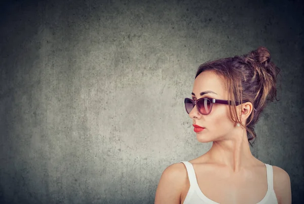 时尚的年轻休闲女人戴着时髦的太阳镜 看着远离灰色背景 — 图库照片
