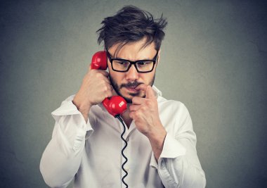 Gri arka plan üzerinde konuşurken sinir görünümlü genç dostum çağrı telefon üzerinde olması ve ısırma gözlükte sinirli tırnak