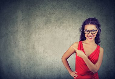 Güzel güzel esmer kırmızı elbise ve uzağa işaret ve kamera reklam gri arka plan üzerinde gösteren gülümseyen bardakları