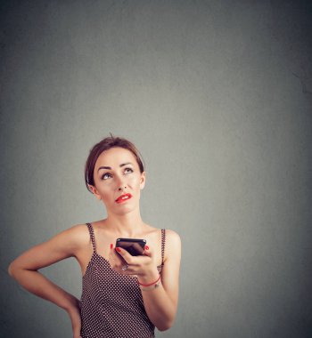 Genç casual kadın yüz buruşturma smartphone üzerinde konuşma ve gri arka plan üzerinde seyir sırasında irritasyon yapma