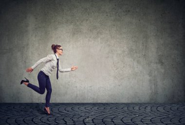 İleri zaman baskısı gri duvar karşı profesyonel rekabet yönetmek isteyen altında çalışan modern resmi iş kadını yan görünüm