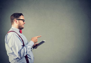 Tablet tutarak ve gri arka plan üzerinde seçiminde uzağa işaret bardaklarda tıknaz adam yan görünüm