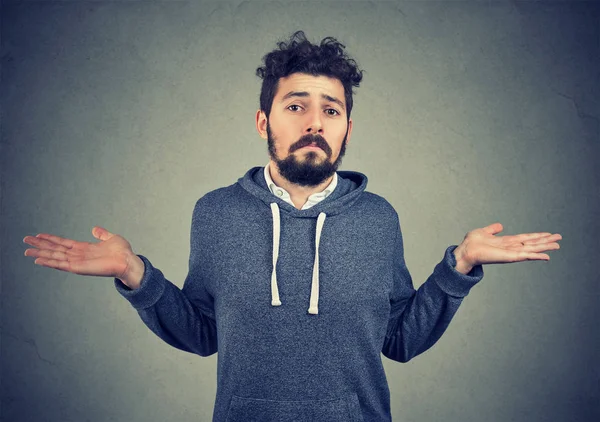 Cehalet ve kibir. Shrugging genç bir adam portresi duygu clueless gri arka plan üzerinde izole omuzlar. Ne olursa olsun tutum tepki