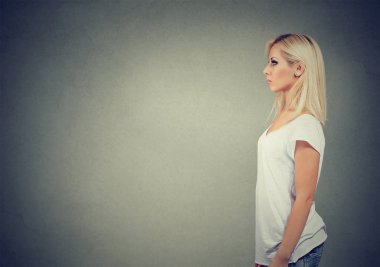 Modern genç kadın rahat kıyafet ayakta gri arka plan üzerinde yan görünüm
