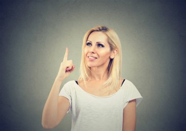 Gri arka plan üzerinde parlak fikir sahip olmak kadar parmak tutan rahat bir kadın portresi