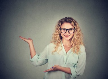 Genç kadın işaret ve gri arka plan üzerinde sunum yapma gözlük