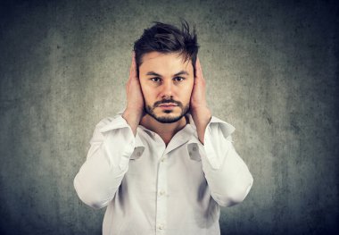 Genç adam gri arka plan üzerinde gürültü önleme kulakları kapsayan