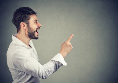 Casual adam beyaz gömlek gri arka plan üzerinde parlak fikir sahip olmak kadar parmak tutan yan görünüm