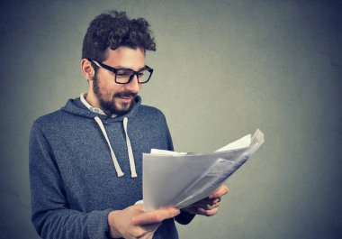 Kağıtları kesin sonuçları ile tutarak ve duygu mutlu gülümseyen bardakları neşeli genç adam 