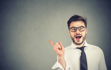 Gözlük ve resmi gömlek işaret uzakta yeni teklif gösterilen ve kameraya gülümseyen yakışıklı genç