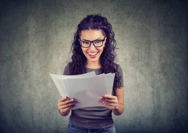 Kağıtları kesin sonuçları ile tutarak ve parlak kameraya gülümseyen bardakları neşeli genç kadın