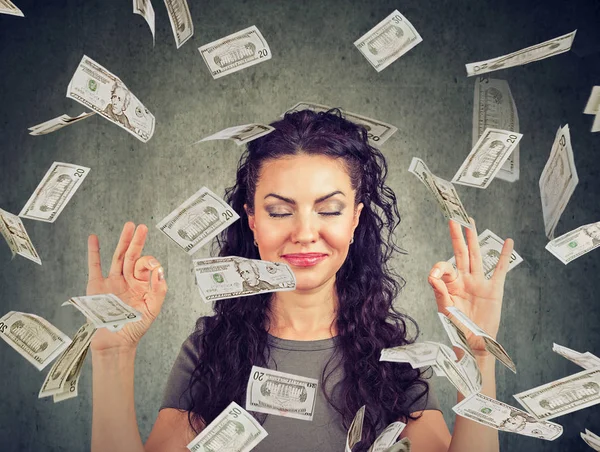 Happy business woman meditating under money rain