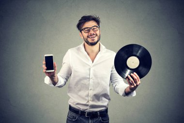 Mutlu hipster sakallı adam holding vinil kaydı diskini ve modern smartphone eski ve yeni teknoloji karşılaştırma 