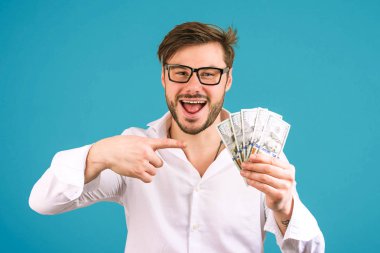 Nakit yığını tutan ve bu mavi arka plan kameraya gülümseyen gösteren Beyaz tişörtlü neşeli başarılı adam