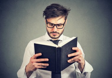Gri arka plan üzerine bir akıllı kitap okuma gözlüklü genç adam