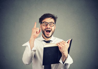 Genç iş adamı parmak kitap gri arka plan üzerinde tutarak harika bir fikir ile heyecanlı dayanabiliyor bardaklarda akıllı