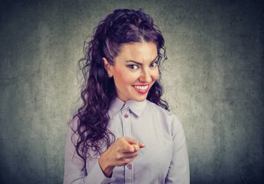 Şirin esmer kameraya seçim yapma ve gri arka plan üzerinde gülümseyen parmakla işaret