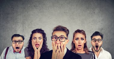 Shocked man in glasses and his scared friends pose against gray wall background. Emotional horrified group people see something unexpected. Human reaction concept clipart