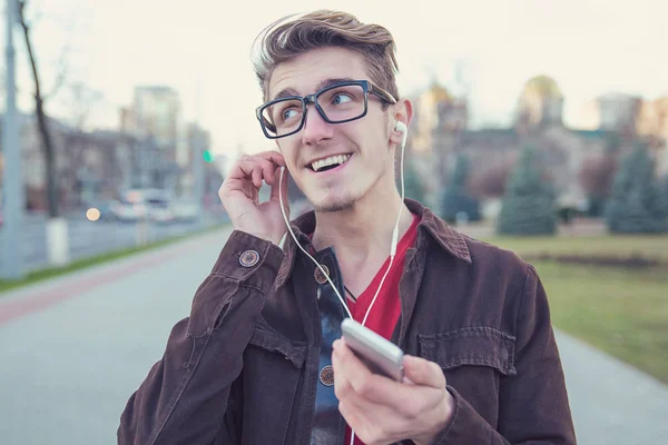 Joven Feliz Gafas Sosteniendo Teléfono Inteligente Escuchando Música Con Auriculares —  Fotos de Stock