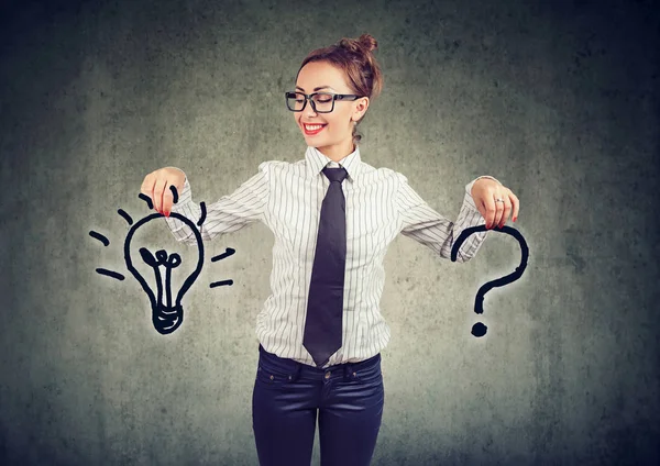 幸せな若いビジネスの女性の質問と灰色の壁の背景に答えアイデア電球と — ストック写真