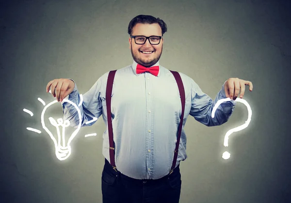 Happy young business man with question and an answer idea light bulb on gray wall background — Stock Image Happy Young Business Man Question Answer Idea Light Bulb Gray Royalty Free Stock Photos