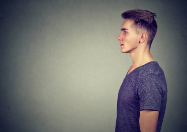T-shirt gri arka plan üzerinde ciddi seyir yetişkin modern insan yan görünüm
