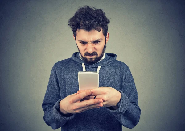 拿着智能手机的留胡子的年轻人对短信感到不安 — 图库照片