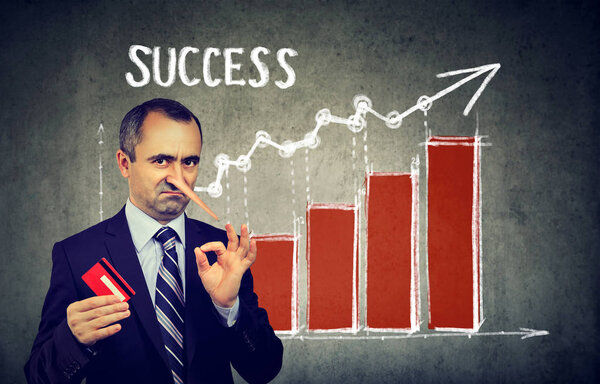 Financial fraud concept. Liar dishonest businessman holding a credit card with big growing Pinocchio nose making a promise of financial success 