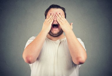 Tombul adam gri arka plan üzerinde heyecan ile sürpriz bekliyor göz kapsayan