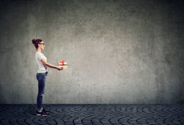 Noel hediye kutusu gri arka plan üzerinde gülümseme ile oldukça gülümseyen kadın yan görünüm