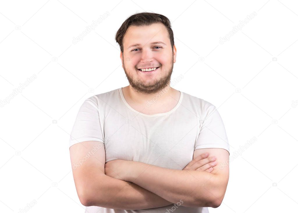 Portrait of young chubby man in white t-shirt holding arms crossed and smiling at camera on white background 