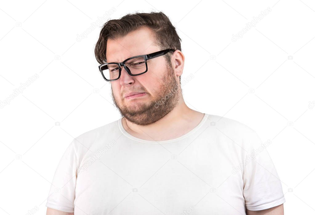 Young bearded man in glasses frowning of bad smell looking deeply displeased on white background