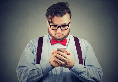 Genç adam smarpthone izliyor ve endişeli ve kötü haber, korkmuş seyir bardaklarda sakallı