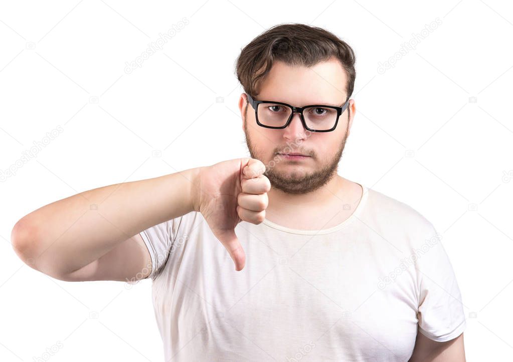 Adult chunky unhappy man in white t-shirt and glasses showing thumb down looking at camera isolated on white background