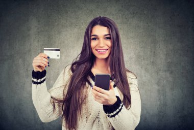 Cep telefonu gri arka plan üzerinde izole tutarken mutlu genç kadın gösteren kredi kartı portresi 